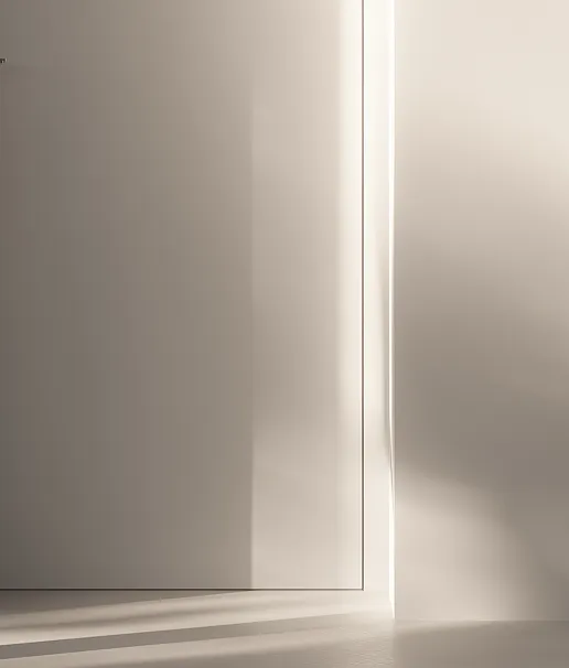 Luce solare morbida che entra da una porta leggermente aperta, creando ombre soffuse su una parete e sul pavimento.