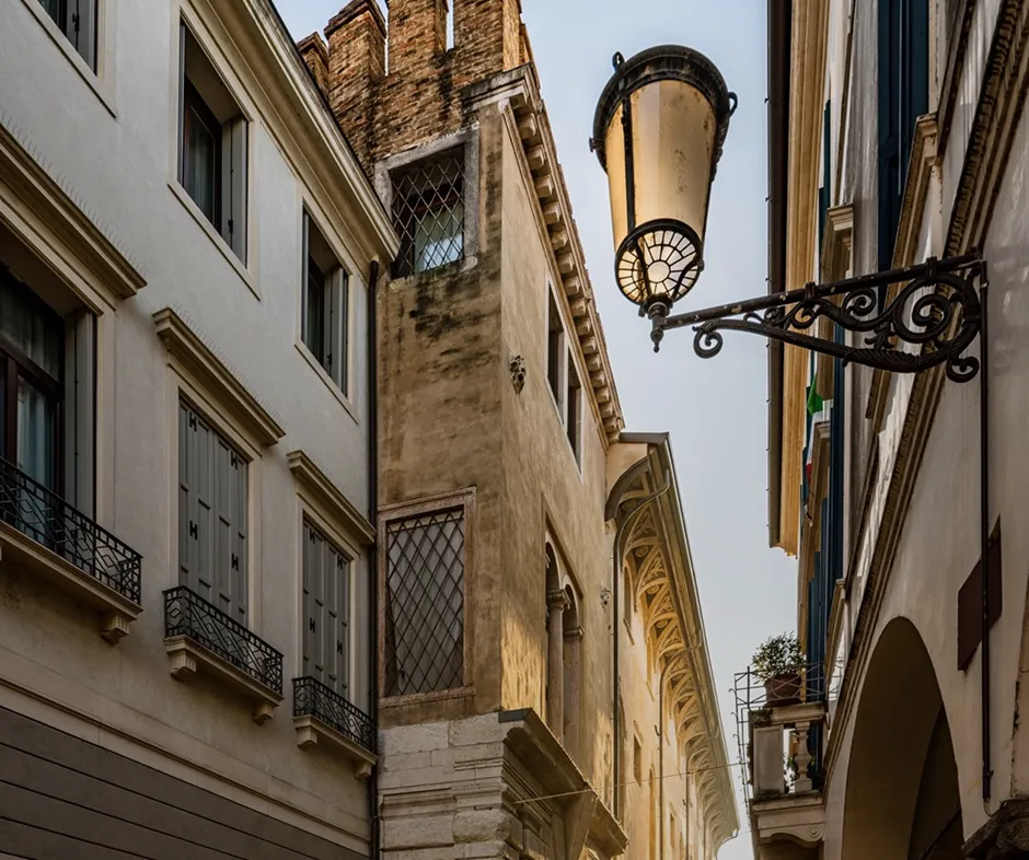 View looking up between narrow historic buildings with a decorative street lamp on the right.