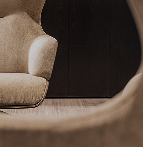 Close-up of beige upholstered armchairs with a dark wooden wall background.